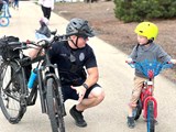 Police Officer on bike patrol talking with a young boy.