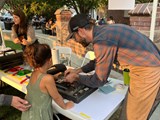 A man teaching a young girl how to use an open press