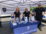 Two Crime Prevention Specialists and a Police Officer doing community outreach at an event.